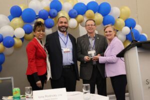 2023 April 29 Cementation Americas represented by Area Director John Cooney and Managing Director Roy Slack accept the Toastmasters International Corporate Appreciation award from International Director Dawn Frail, DTM. Iona Rodricks, District Director, DTM congratulates.